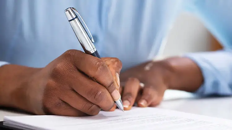 A person signing a paper contract with a pen