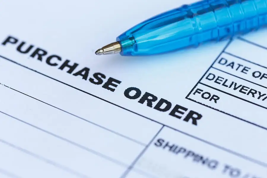 Blue pen resting on a printed purchase order form